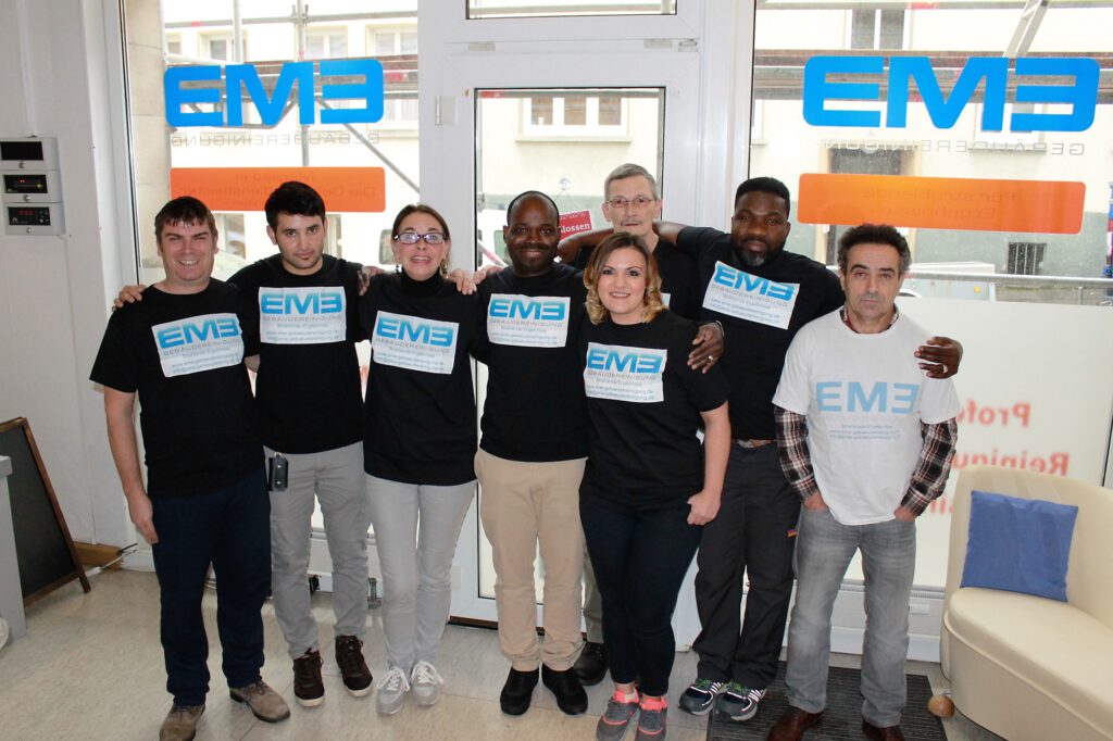 Mitarbeiter der EME Gebäudereinigung bei der professionellen Glasreinigung einer Fensterfläche mit einem Abzieher.