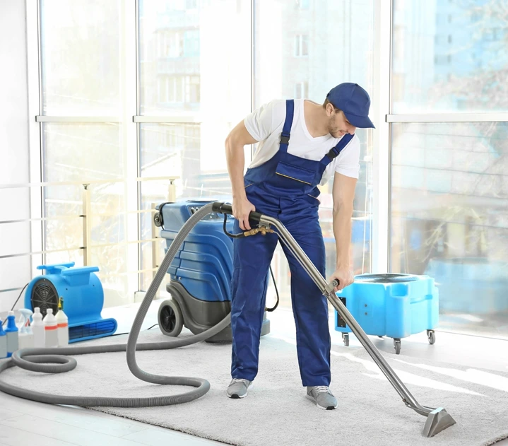 Ein Mitarbeiter nutzt ein professionelles Reinigungsgerät zur Tiefenreinigung eines Teppichbodens.