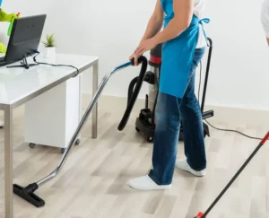 Reinigungsteam bei der Desinfektion von Schreibtischen und der Bodenpflege mit Industriestaubsaugern.